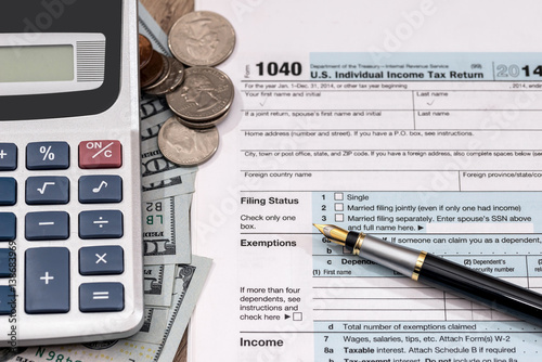 U.S. 1040 tax return form with dollar, pen and calculator.
