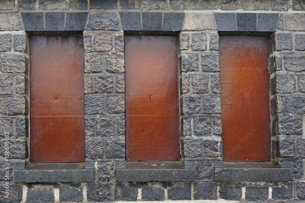 Mit rostigen Metallplatten verschlossene Fenster in einem alten Gemäuer. Mit rostigen Metallplatten verschlossene Fenster in einem alten Gemäuer.