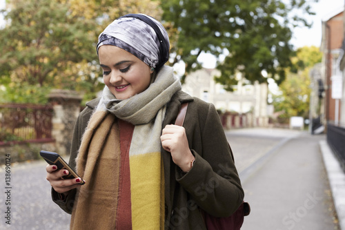 British Muslim Woman Using Mobile Phone In Urban Setting © Monkey Business