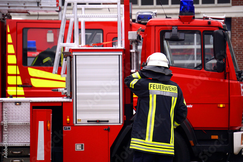 Ein Feuerwehrmann vor einem modernen Feuerwehrfahrzeug bei einem Feuerwehreinsatz.