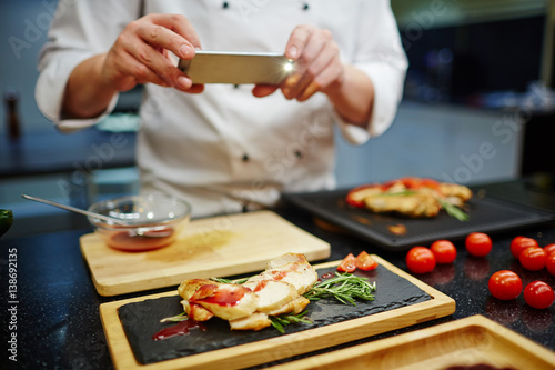 Obraz na plátně Chef photographing roasted chicken steak dressed by tomato sauce
