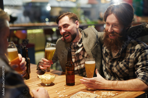 Group of men drinking beer and having talk in pub