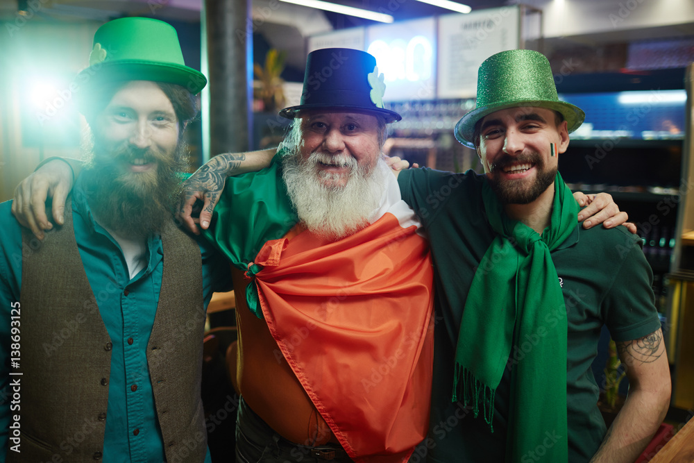 Three happy buddies in Irish costumes in pub