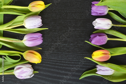Fototapeta Naklejka Na Ścianę i Meble -  Wooden black background with fresh colourful purple, lilac, yellow,re, orange, spring tulips and empty copy space