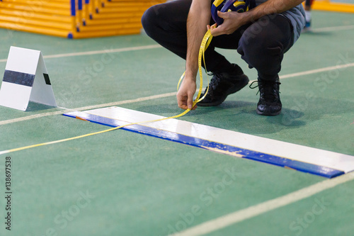An official taking measure of long or triple jump on track and field competition photo
