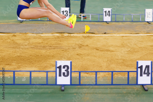 Sportswoman jumping into sandpit on triple jump competition in track and field championship photo