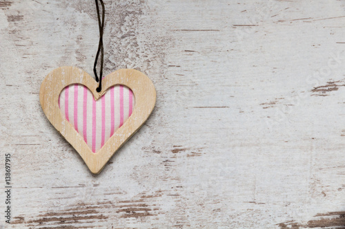pink colored wooden heart on white wooden background