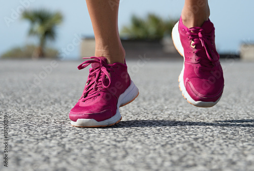 Runner woman feet running on road training for fitness and healthy lifestyle