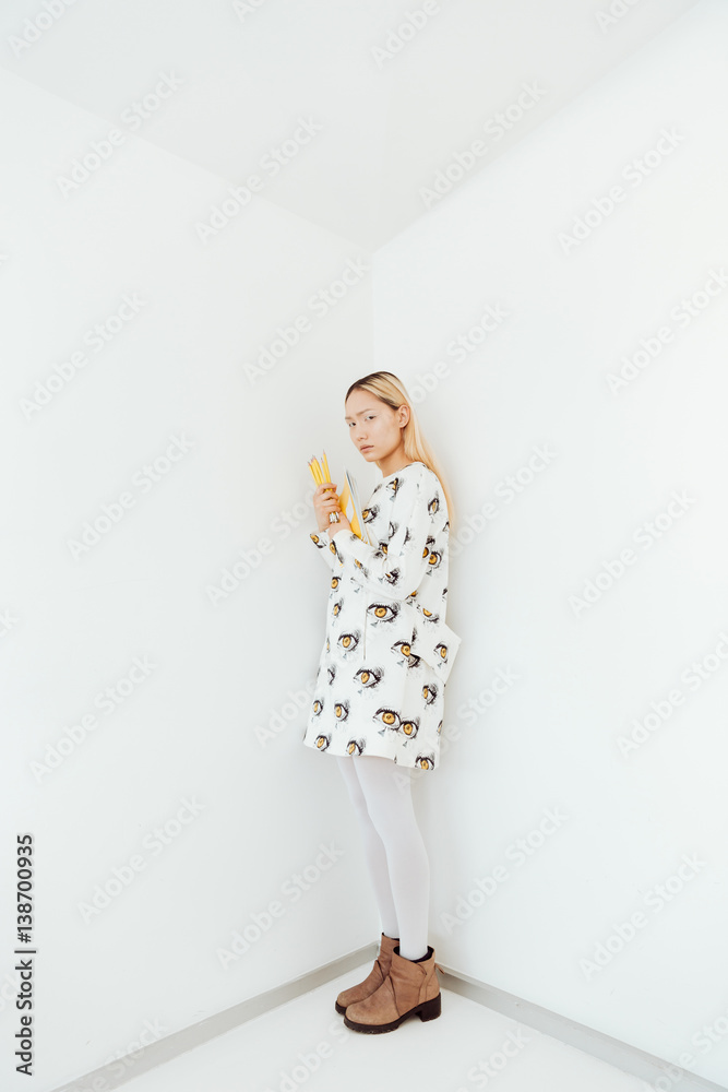 Serious young asian lady standing over wall with pencils Serious young asian lady standing over wall with pencils