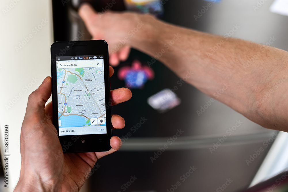 Person hands holding smartphone and searching for places to eat on map