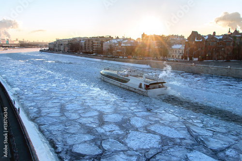 pleasure boat floats on the river covered with ice