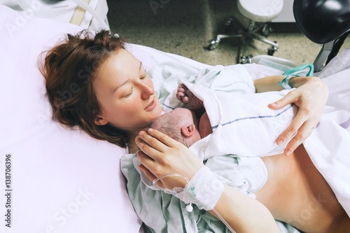Mother holding her newborn baby after labor in a hospital.