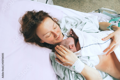 Mother holding her newborn baby after labor in a hospital. photo