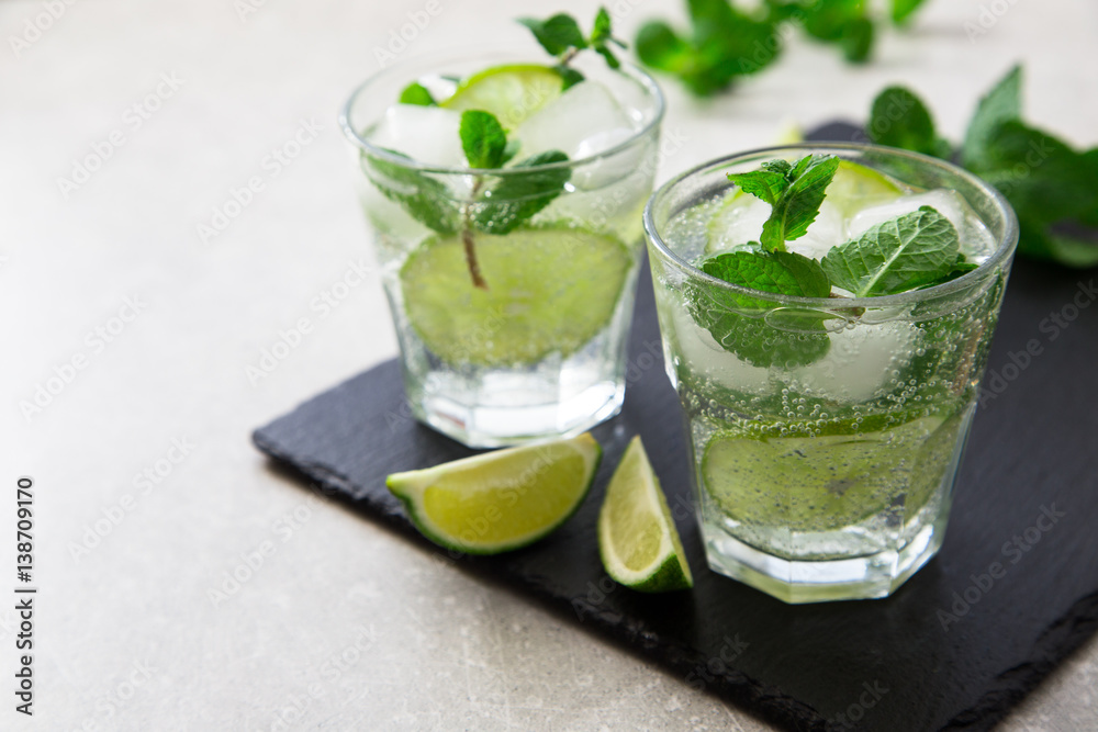 Cold refreshing summer lemonade mojito in a glass on a slate board and stone background.
