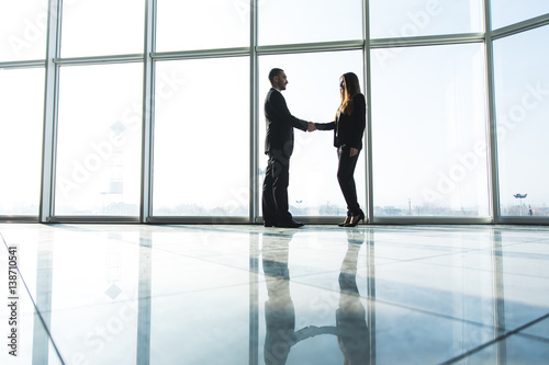 business people shaking hands over office background