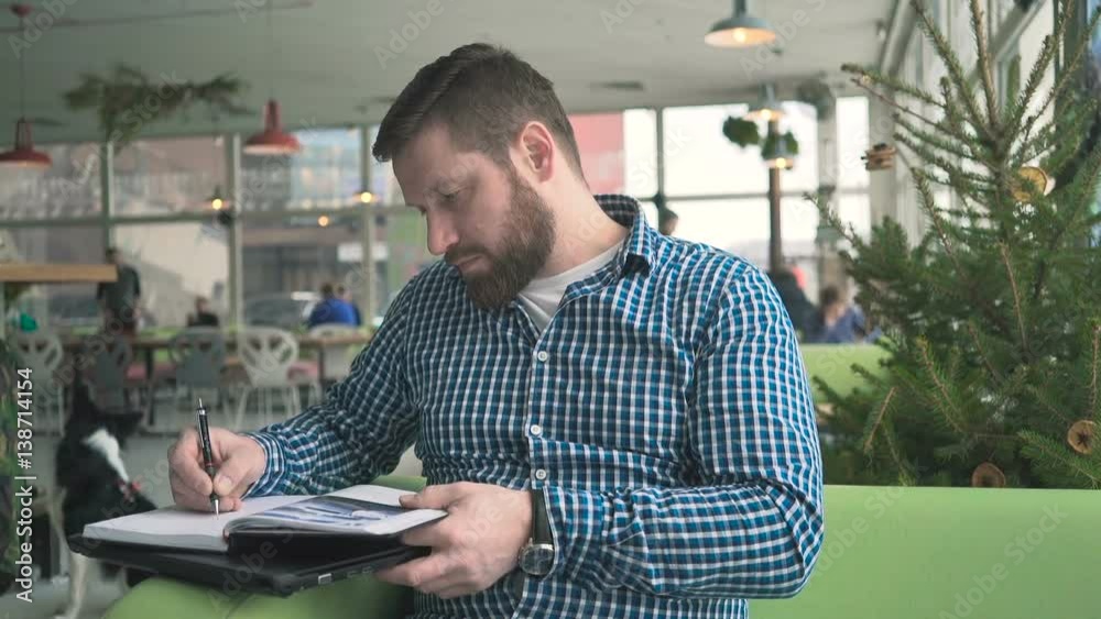 Man make notes in calendar, look at camera, cafe, portrait, steadycam Man make notes in calendar, look at camera, cafe, portrait, steadycam