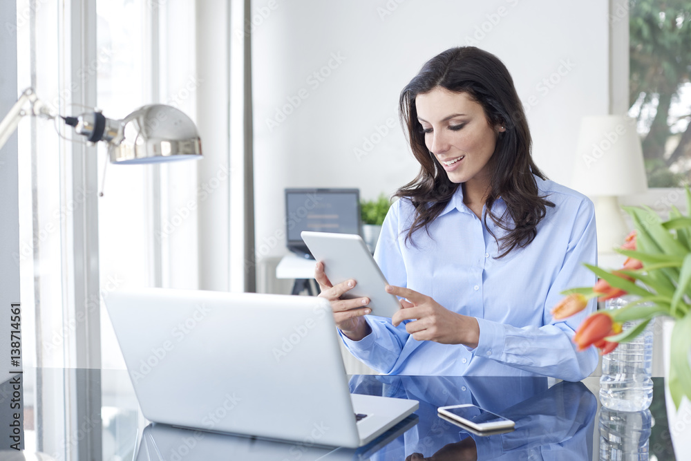 Working from home. Shot of a careworn businesswoman using her digital tablet while sitting in home office. Working from home. Shot of a careworn businesswoman using her digital tablet while sitting in home office.