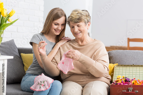 Bilde på lerret Young woman watching her grandma embroider