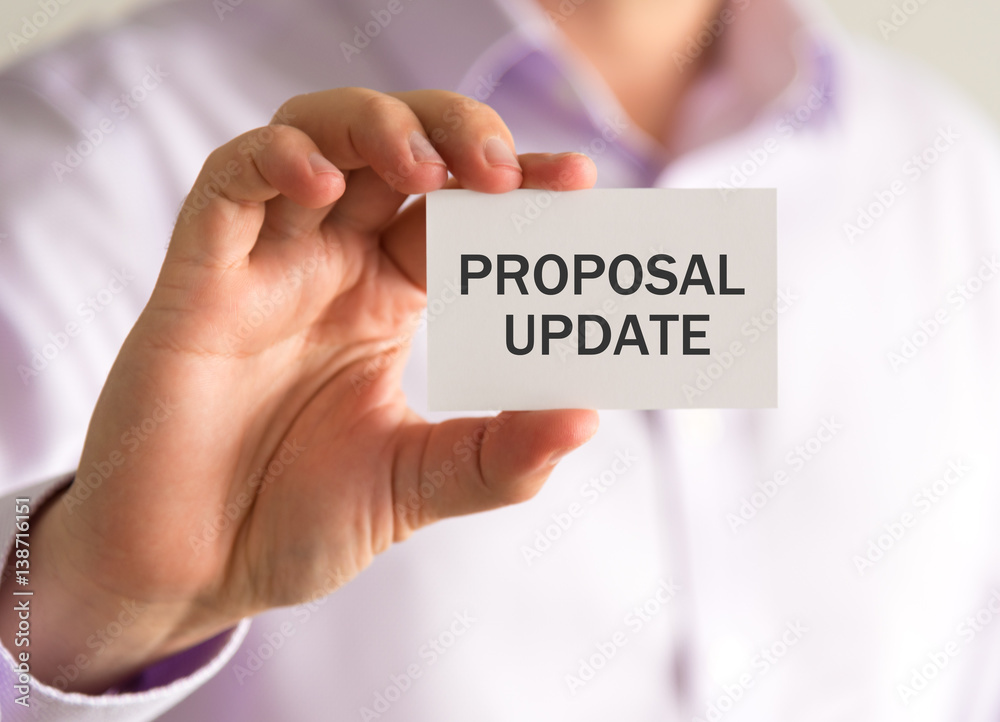 Businessman holding a card with PROPOSAL UPDATE message Businessman holding a card with PROPOSAL UPDATE message