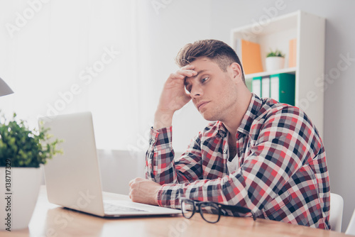 Overworked young man thinking how to solve difficult task at work photo