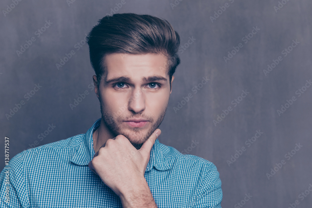 Partrait of handsome minded man touching his chin and looking at camera