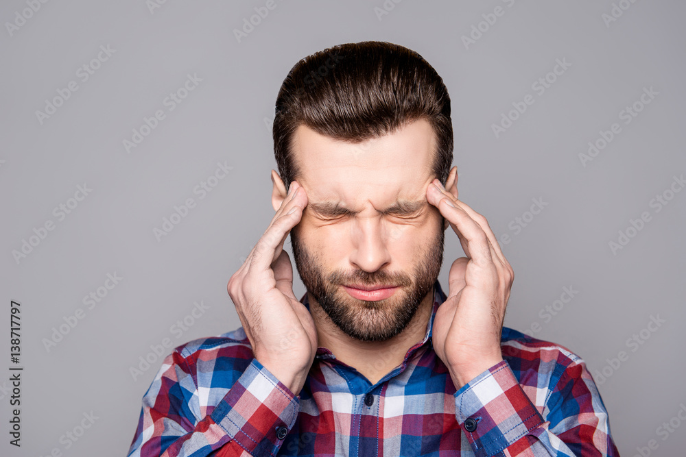 A close up portrait of a young worker in checkered shirt suffering from sudden headache A close up portrait of a young worker in checkered shirt suffering from sudden headache