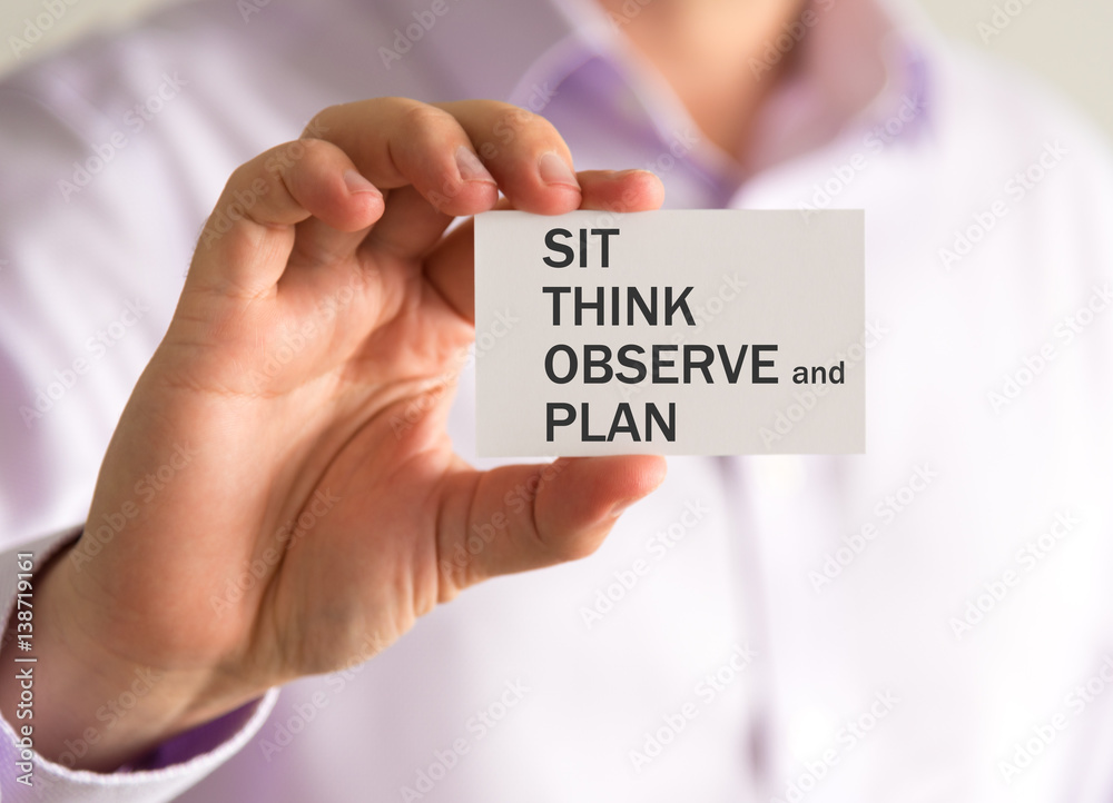 Businessman holding a card with SIT THINK OBSERVE AND PLAN message Businessman holding a card with SIT THINK OBSERVE AND PLAN message