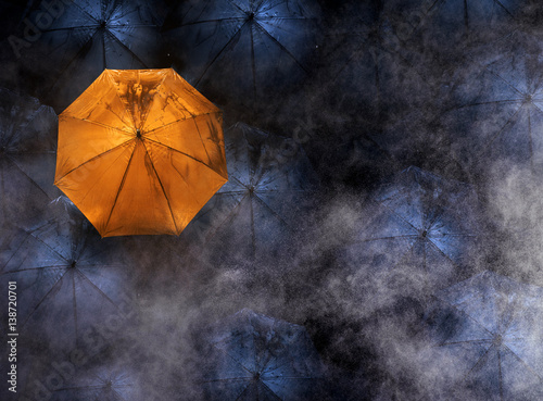 abstract concept of leader with with many dark and a orange umbrella.