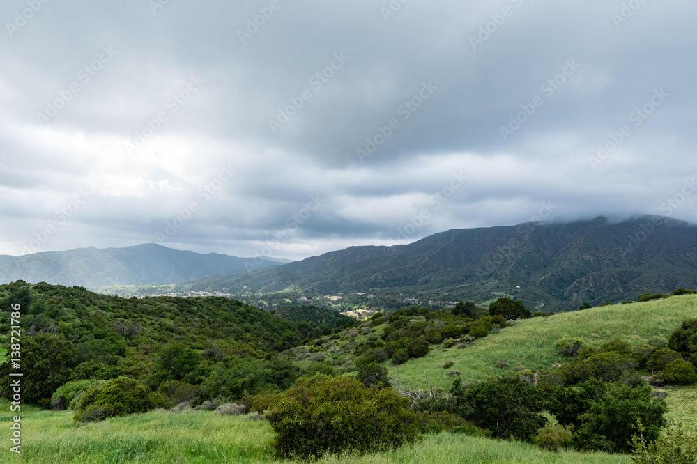 Fototapeta premium Dark clouds over a green valley.