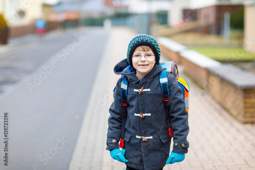 Little kid boy with eye glasses walking from the school