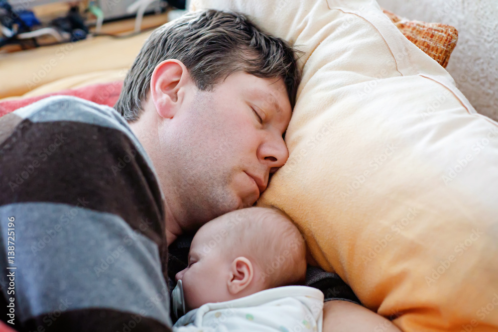 Middle aged father sleeping near his newborn baby daughter Middle aged father sleeping near his newborn baby daughter