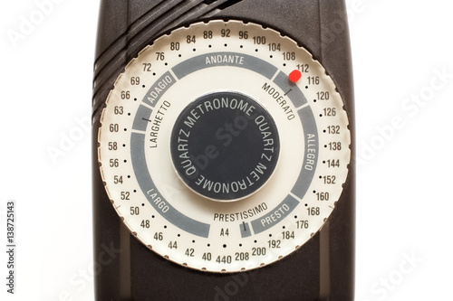 Black metronome with white dial closeup on pure white background.