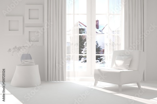 White room with armchair and winter landscape in window. Scandinavian interior design