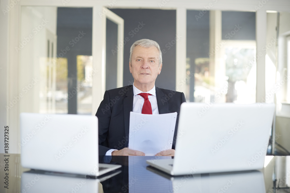 Financial businessman working online. Shot of a senior financial director sitting at desk and working on laptops in the office. Financial businessman working online. Shot of a senior financial director sitting at desk and working on laptops in the office.