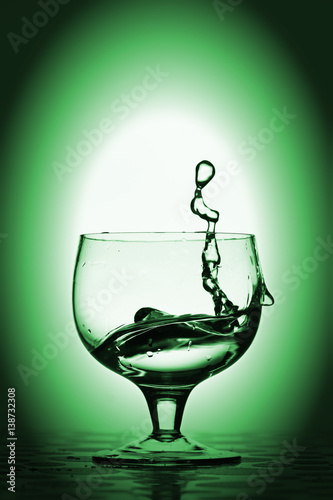 Water splash in glass, green background.
