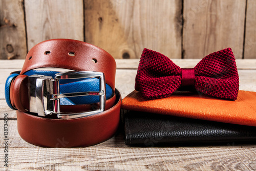 Orange wallet with male accessories on wooden background