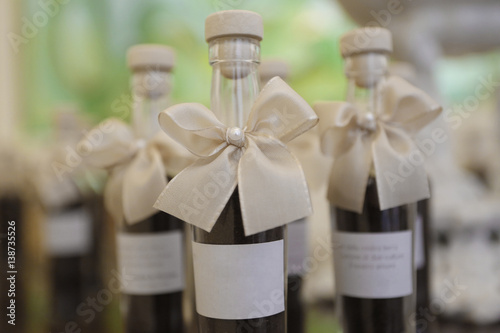 Bottiglie con contenuto scuro con fiocco decorativo e etichetta bianca photo
