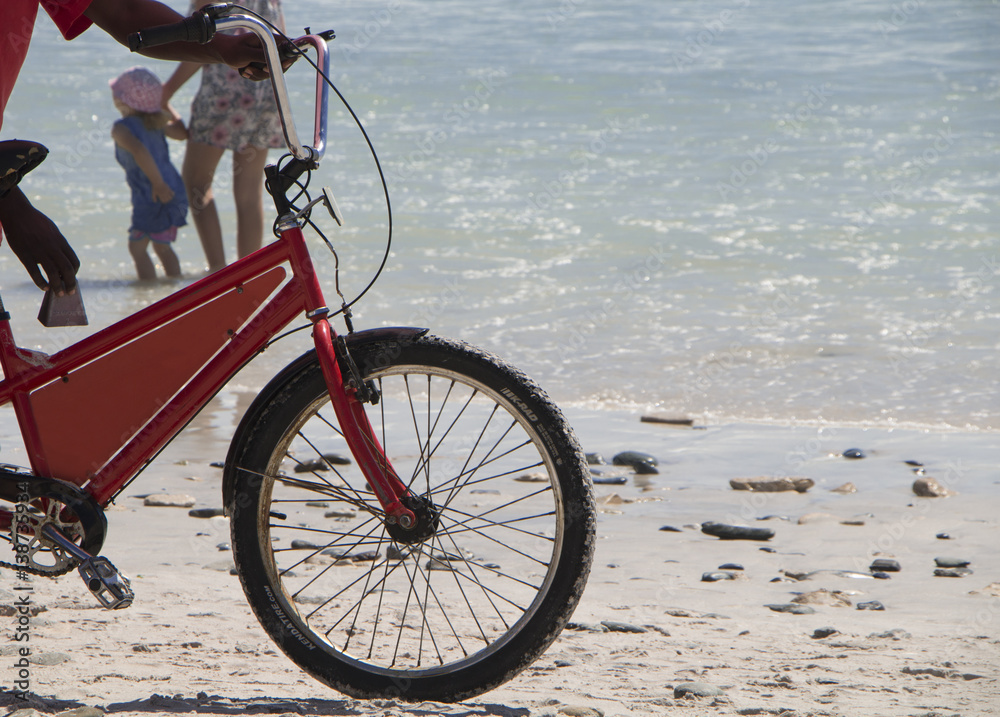 Fototapeta premium ice cream bicycle on beach with child and mother in background
