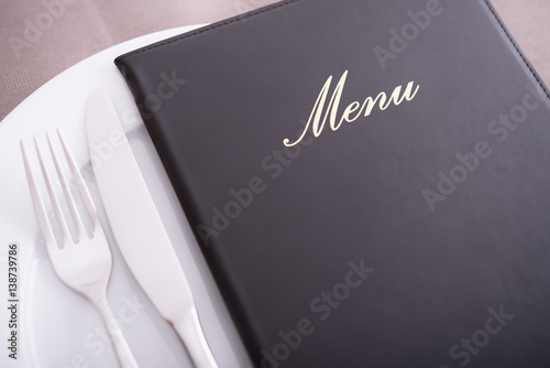 Closeup on menu, arranged table with cutlery and dishes