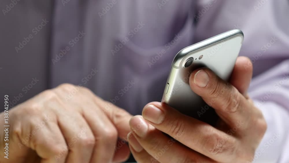 Elderly Man Using Smartphone While Sitting At The Table Elderly Man Using Smartphone While Sitting At The Table