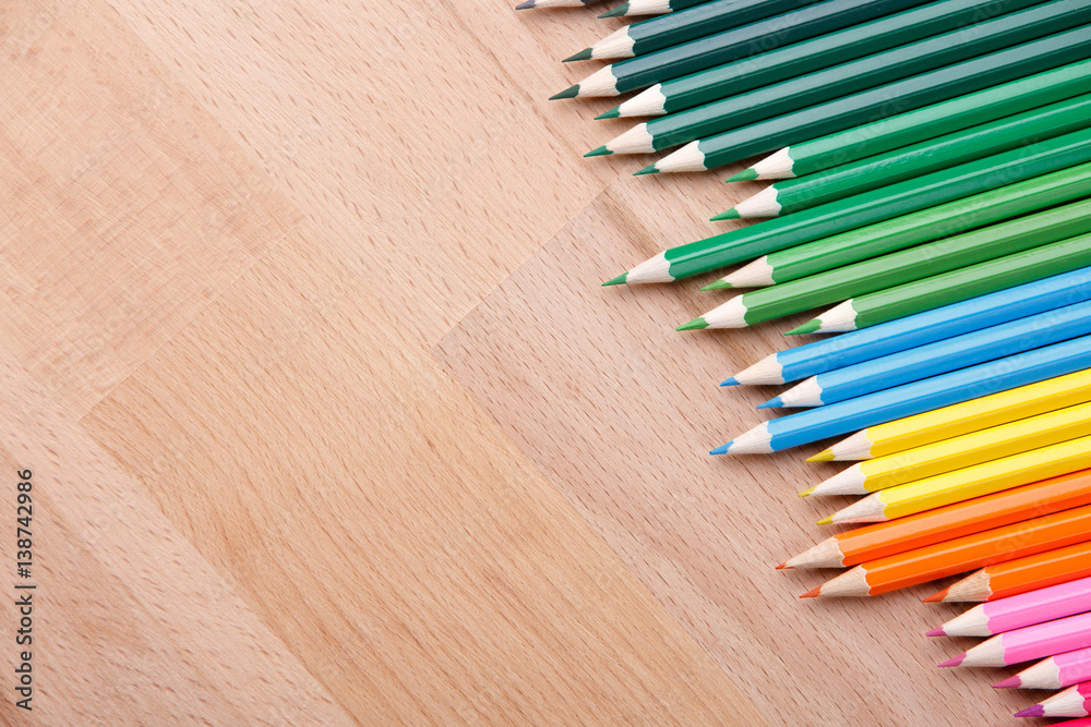 Row of colorful pencils on wooden background