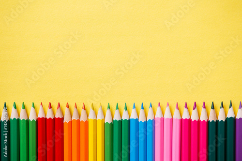 Row of colorful pencils on yellow background