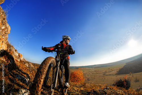 Fototapeta Naklejka Na Ścianę i Meble -  Cyclist Riding the Bike Down Rocky Hill at Sunset. Close up Extreme Sport Concept. Space for Text.