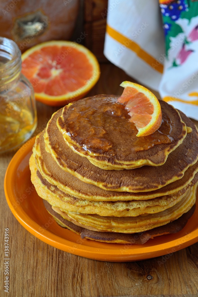 Pumpkin pancakes with orange syrup on the plate.