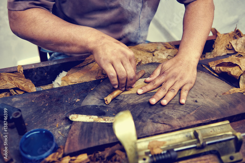 Closeup of hands making cigar from tobacco leaves. Traditional manufacture of cigars. Dominican Republic photo