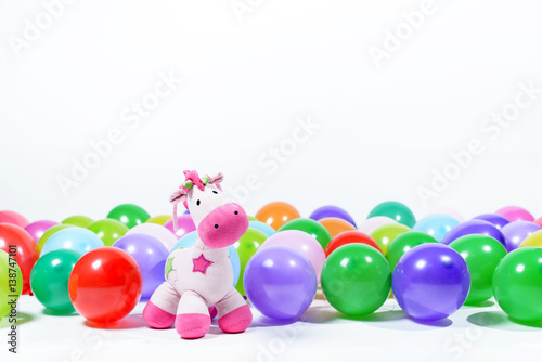 Pink toy horse with multi-colored balloons on a white background