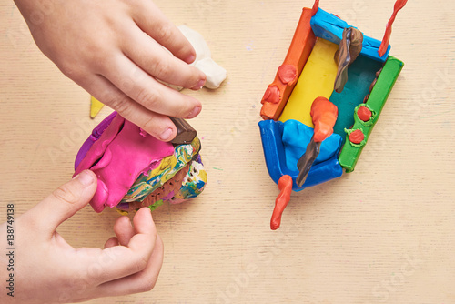 Kid is sculpting with colorful modelling clay. Close up. View from the top.