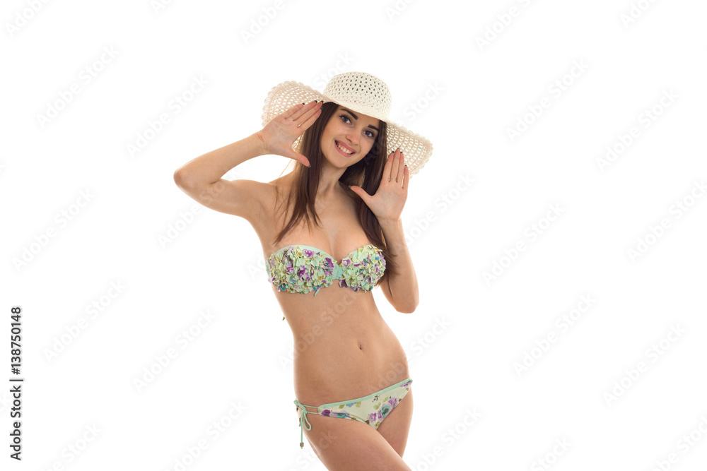 beautiful young girl in a bathing suit with hat on your head looks into the camera and smiling