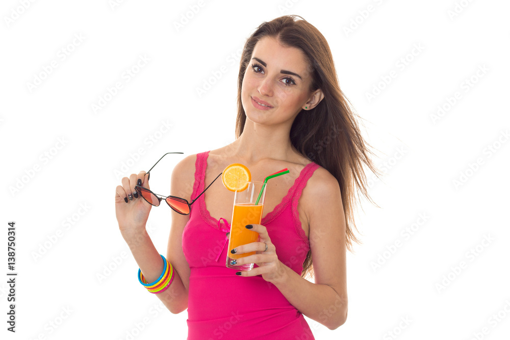 beautiful young girl in pink t-shirt looks straight and holding a glass of juice and glasses beautiful young girl in pink t-shirt looks straight and holding a glass of juice and glasses