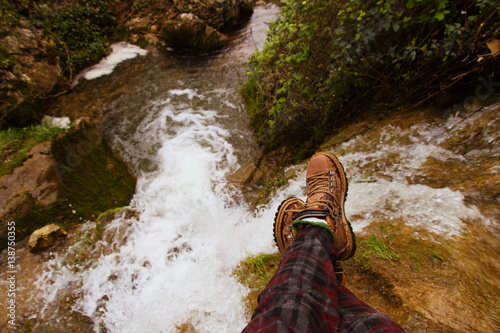 Imagen en primera persona de las piernas de alguien sentada sobre una cascada  photo